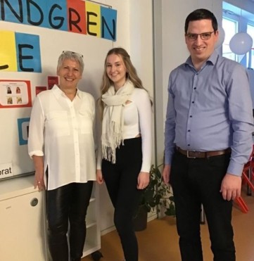 In der Aula der Schule vor einer Plakatwand links die Rektorin Ulla Böhm, daneben Chiara Hensel und rechts steht Hauptamtsleiter Andreas Krebs.