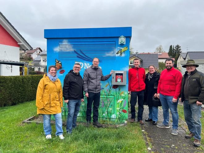 Von links nach rechts stehen vor dem bunt bemalten POP in der Schwarzwaldstraße Margrita Bahn, Mathias Schleicher, Bürgermeister Torben Dorn, Philipp Förg, Nicole Schill, Andreas Schlenker und Franz Schleicher (von links nach rechts) bei der Übergabe des Defibrillators.