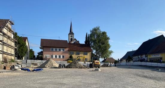 Baustelle auf dem künftigen Dorfplatz. Aufgeschotterte Fläche rechts das gelbe Gebäude der La Trattoria und daneben das Fachwerkhaus in dem sich Lillys Asia Restaurant befindet.
