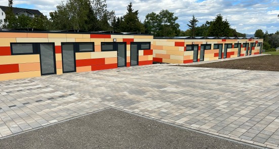 Wohncubes, Flachdachgebäuden mit orange, gelb, rötlicher Fassade und modernen grauen Fenstern.