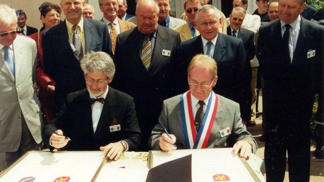 Die ehemaligen Bürgermeister Anton Bruder und Bernhard Ritter sitzen nebeneinander an einem Tisch und unterzeichnen die Patenschaftsurkunde