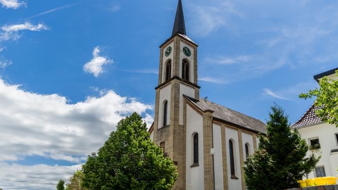 Der Kirchturm der katholischen Kirche ragt in den strahlend blauen Himmel Der Kirchturm der katholischen Kirche ragt in den strahlend blauen Himmel