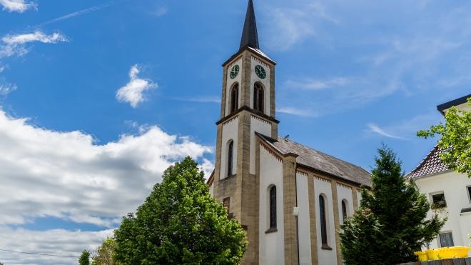 Der Kirchturm der katholischen Kirche ragt in den strahlend blauen Himmel