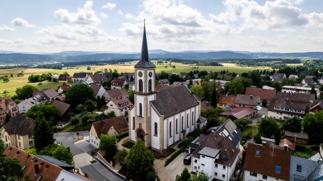 Eine Aufnahme der Katholischen Kirche umgeben von Wohnhäusern, Wiesen und Feldern. Eine Aufnahme der Katholischen Kirche umgeben von Wohnhäusern, Wiesen und Feldern.