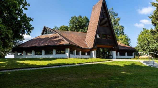 Zeigt die Evangelische Kirche im Tageslicht umgeben von Bäumen und Wiese Zeigt die Evangelische Kirche im Tageslicht umgeben von Bäumen und Wiese