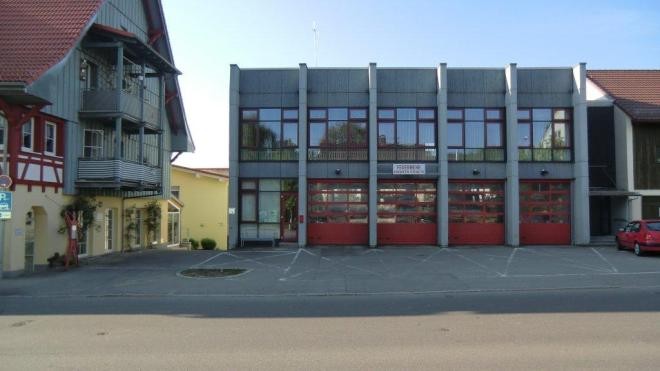 Das Feuerwehrgebäude vor dem Umbau, der Erweiterung, graues Flachdachgebäude mit roten Toren.