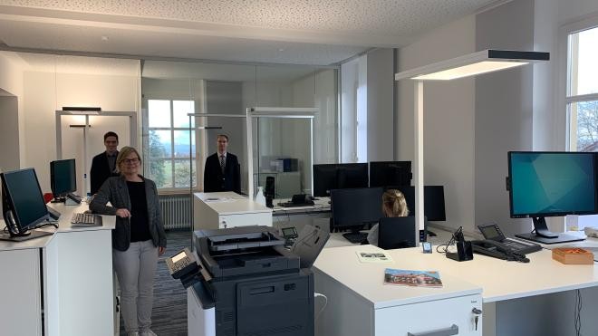 Frau Bächle, Herr Krebs und Bürgermeister Dorn stehen im neuen, sehr modernen Bürgerbüro vor dem neuen verglasten Backoffice.