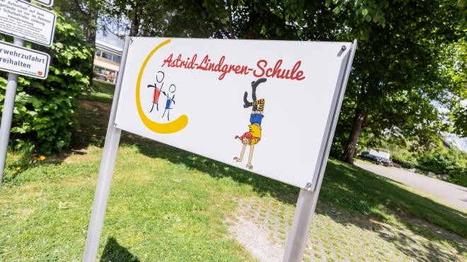 Ein Schild vor einem Baum im Zufahrtsbereich der Schule. Auf dem Schild steht "Astrid-Lindgren-Schule".