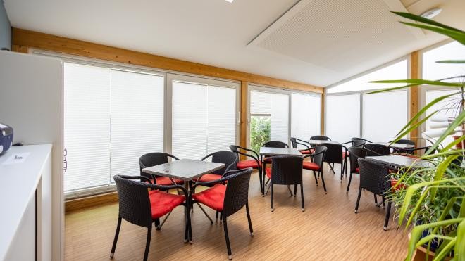 Hier sieht man den Wintergarten von innen, ausgestattet mit Tischen und Stühlen Hier sieht man den Wintergarten von innen, ausgestattet mit Tischen und Stühlen