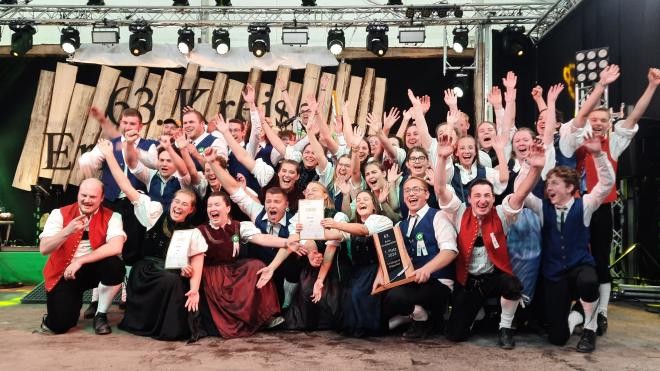Die Mitglieder der Landjugend in ihren Trachten reissen die Hände vor Freude in die Luft.