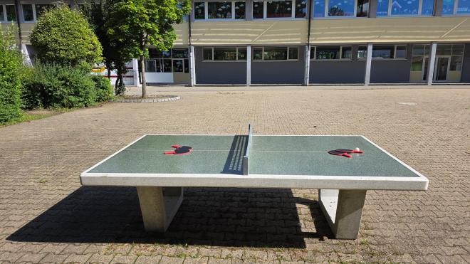 Tischtennisplatte auf dem Schulhof im Hintergrund die Astrid-Lindgren-Schule.