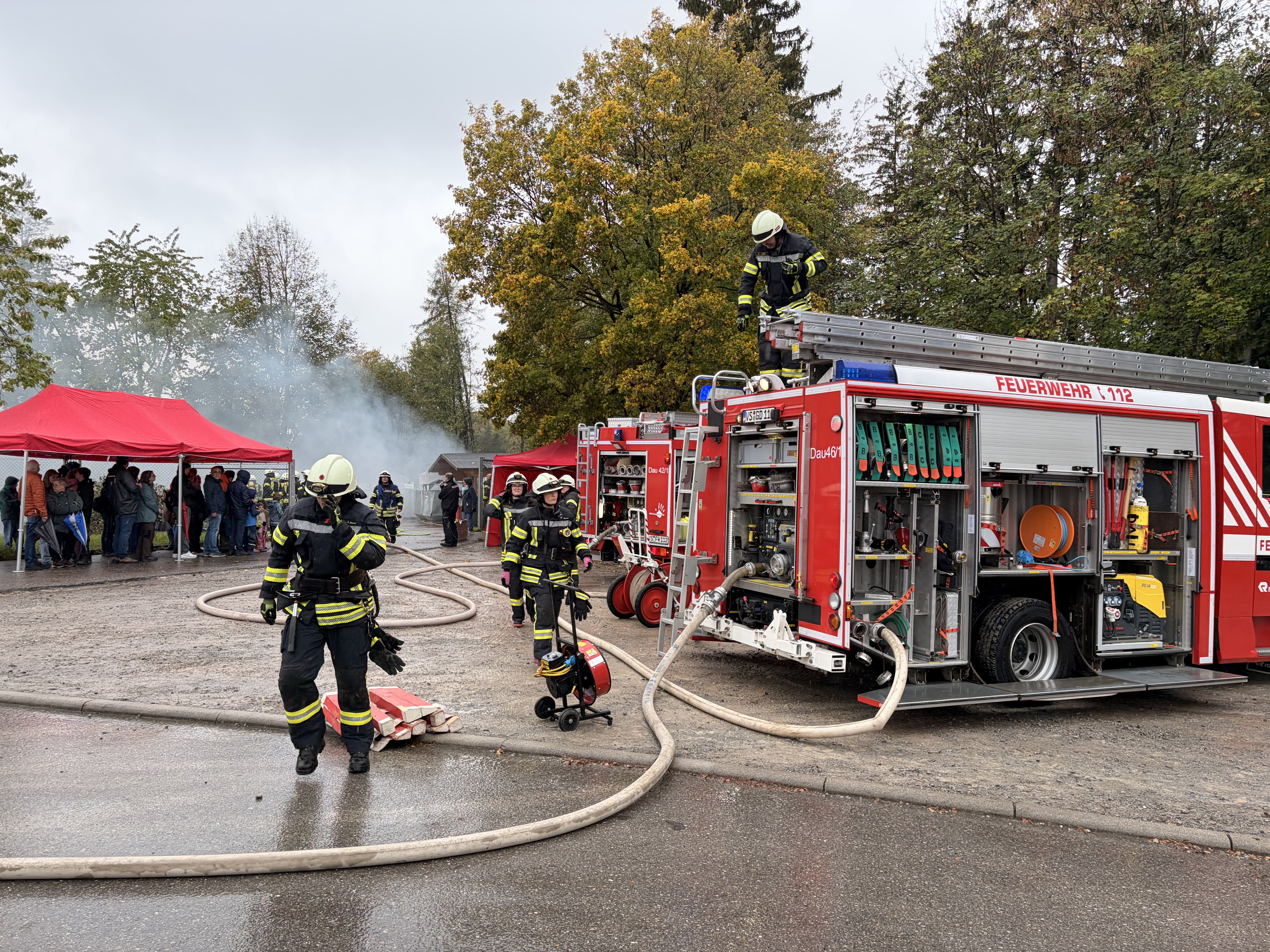 Aufgereihte Feuerwehrfahrzeuge die geöffnet sind und aus denen Schläuche gezogen wurden.
